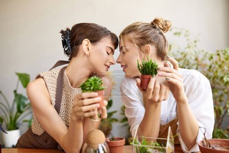 Zwei Frauen genießen einen ruhigen Moment an einem Tisch umgeben von Topfpflanzen in ihrem Kunstatelier.