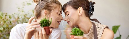 Photo for Two women lovingly hold plants in an art studio. - Royalty Free Image