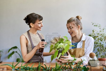 Lesbian couple in aprons appreciating greenery in art studio.