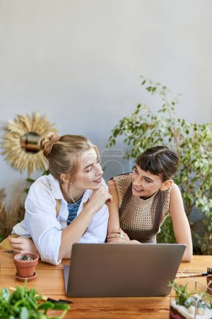 Téléchargez les photos : Deux femmes immergées dans la créativité, travaillant ensemble sur un ordinateur portable dans un studio d'art. - en image libre de droit