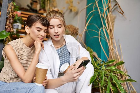 Zarte lesbische Paar teilen einen Moment, vertieft in Handy.