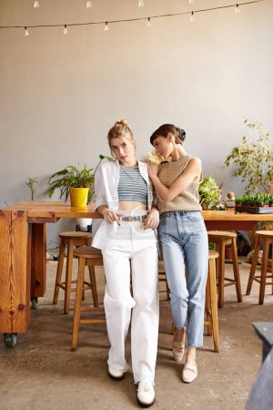 Téléchargez les photos : Un couple lesbien tendre et aimant se tient dans un studio d'art, entouré de créativité. - en image libre de droit