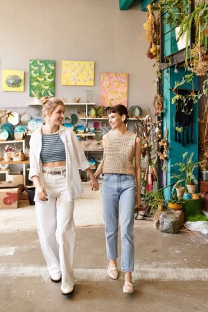 Two women gracefully walk in a room surrounded by lush plants.