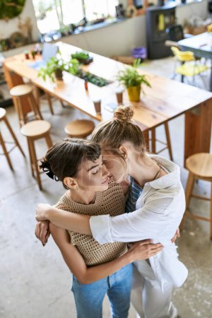 Two women share a warm embrace in a cozy restaurant setting.