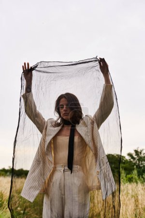 Eine schöne junge Frau in weißem Gewand steht auf einem Feld, die Hände in der Luft und umarmt die Freiheit und Schönheit der Natur..
