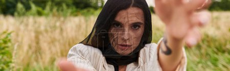 Photo for A woman in a white shirt and black veil, soaking in the gentle summer breeze in a field of nature. - Royalty Free Image