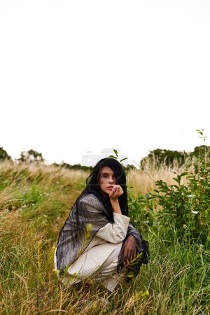 Una hermosa joven vestida de blanco arrodillada en un campo de hierba alta, disfrutando de la brisa del verano.
