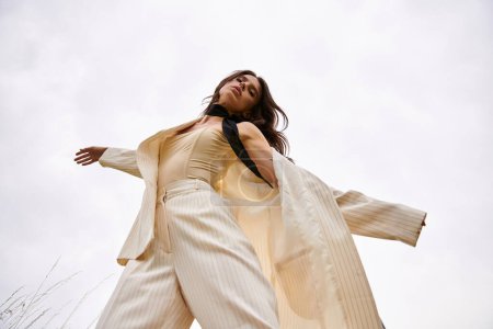 A beautiful young woman in a white suit gracefully flying through the air in a serene field, enjoying the summer breeze.