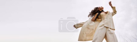 Foto de Una joven con un traje blanco que vuela con gracia por el aire, disfrutando de la brisa del verano en un entorno natural. - Imagen libre de derechos