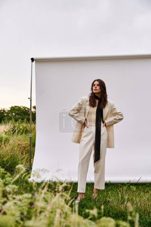 A beautiful young woman in white attire standing in a field, feeling the summer breeze against a white backdrop.
