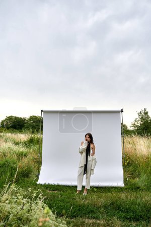 Una joven se levanta con gracia frente a una pantalla blanca, encarnando una sensación de elegancia y serenidad en un entorno natural.