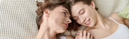 Photo for A beautiful lesbian couple in comfy attire, laying peacefully side by side on a bed. - Royalty Free Image