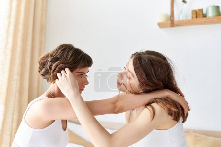 Two women in a bedroom, embracing each other warmly.