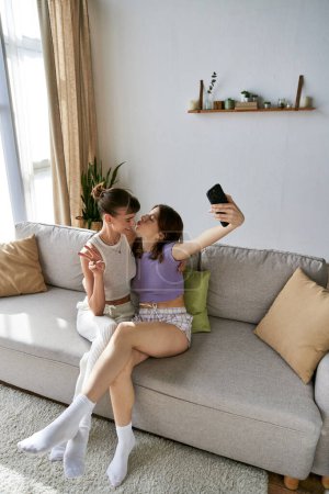 Téléchargez les photos : Deux femmes en vêtements confortables assises ensemble sur un canapé. - en image libre de droit