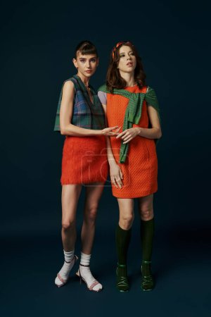 Téléchargez les photos : Un couple lesbien se tient côte à côte dans des robes orange assorties, exsudant harmonie et confort. - en image libre de droit