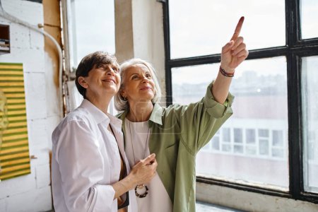 Two mature women sharing a moment of togetherness in an art studio.