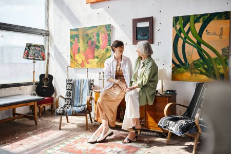 Téléchargez les photos : Mature lesbian couple engaged in conversation in an art studio. - en image libre de droit