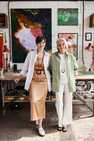 Two mature women standing peacefully in an art studio.