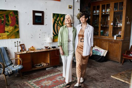 Foto de Mature lesbian couple standing together in an art studio. - Imagen libre de derechos