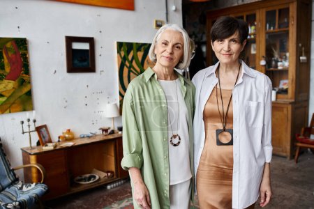 Mature lesbian couple standing in art studio together.