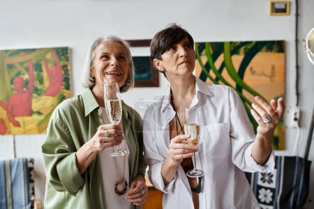 Foto de Two sophisticated women happily holding wine glasses. - Imagen libre de derechos