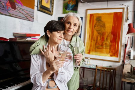 Two mature women enjoying wine in art studio.