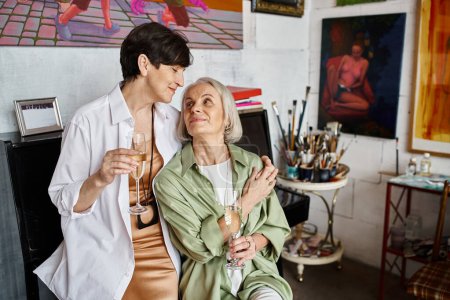 Foto de Woman holding wine glass beside her partner in artistic setting. - Imagen libre de derechos