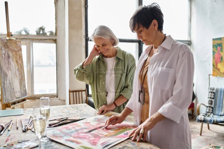 Photo for Two older women admiring artwork in an art studio. - Royalty Free Image