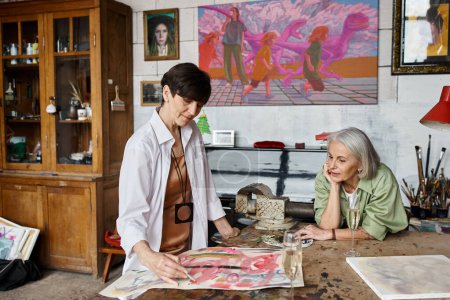 Foto de Dos mujeres admiran una pintura en un estudio de arte. - Imagen libre de derechos