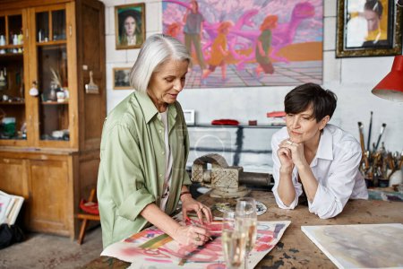 Téléchargez les photos : Deux femmes peignent joyeusement ensemble dans un atelier confortable. - en image libre de droit