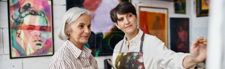 Foto de Dos mujeres admiran las pinturas en una sala de galería. - Imagen libre de derechos