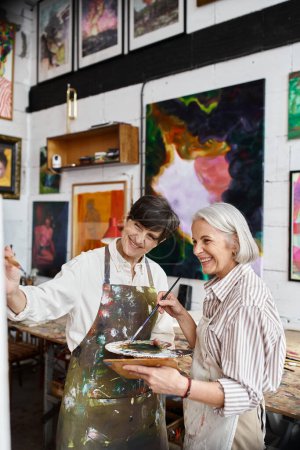 Two women paint in an art studio together.