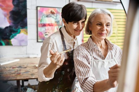 Two women painting together in an art studio.