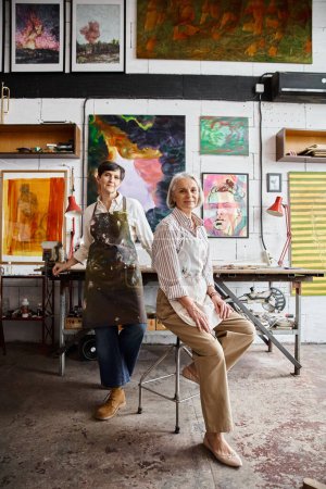 Foto de Dos mujeres admiran las pinturas en un estudio de arte. - Imagen libre de derechos