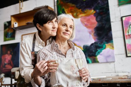 Two women holding wine glasses in art studio.