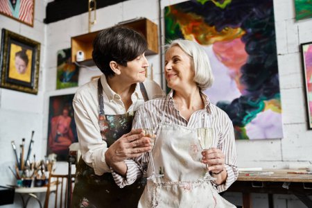 Mature lesbian couple standing together in an art studio.