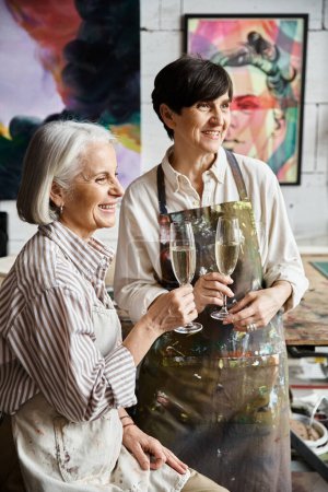 Two women enjoying wine together in art studio.