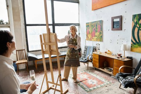 Woman standing at easel holding wine glass, painting partner.