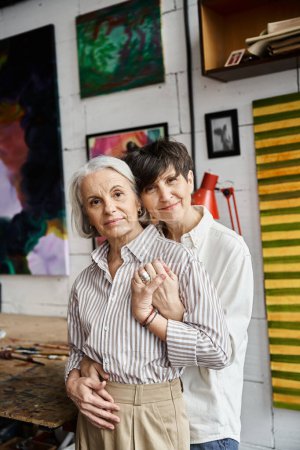 Foto de A mature lesbian couple standing together in an art studio. - Imagen libre de derechos