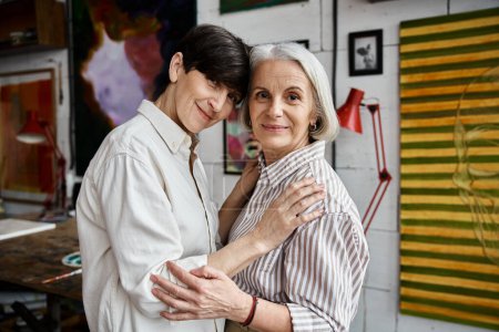 Two women with arms wrapped around each other in a cozy room.