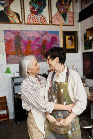 Two women, a mature lesbian couple, collaborate in an art studio.