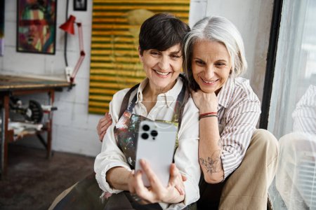 Photo for Two women joyfully taking a selfie with phone. - Royalty Free Image