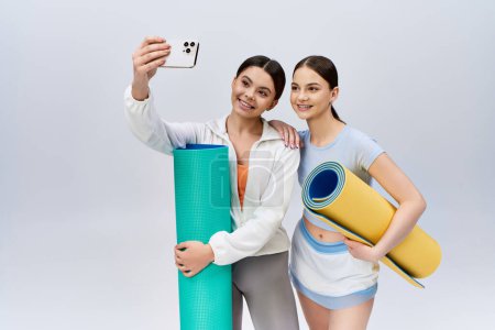 Foto de Dos guapas adolescentes morenas vestidas con ropa deportiva se paran una al lado de la otra en un estudio. - Imagen libre de derechos