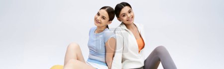 Photo for Two pretty, brunette teenage girls in sportive attire sitting closely together, showcasing friendship and camaraderie. - Royalty Free Image