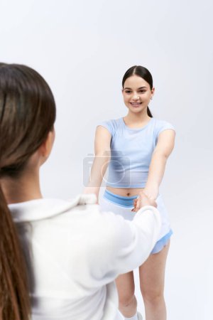 Photo for A brunette woman in a blue top and skirt stands in front of a friend - Royalty Free Image