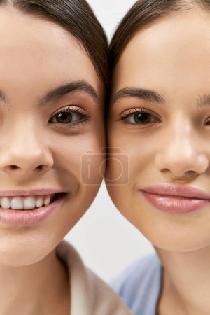 Photo for Two pretty and brunette teenage girls take a selfie in a studio against a grey background. - Royalty Free Image