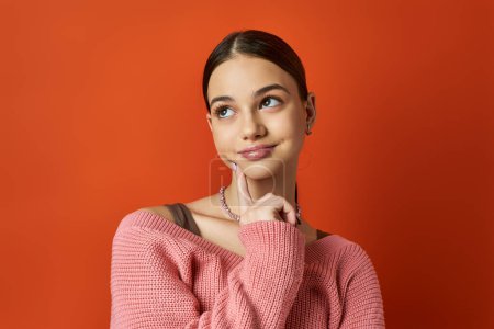 Téléchargez les photos : Une adolescente brune en pull rose pose pour une photo dans un cadre studio vibrant. - en image libre de droit