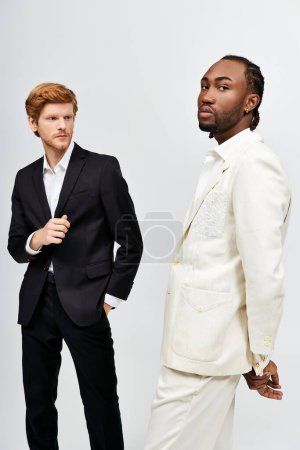 Foto de Dos hombres guapos en trajes elegantes se paran uno al lado del otro. - Imagen libre de derechos