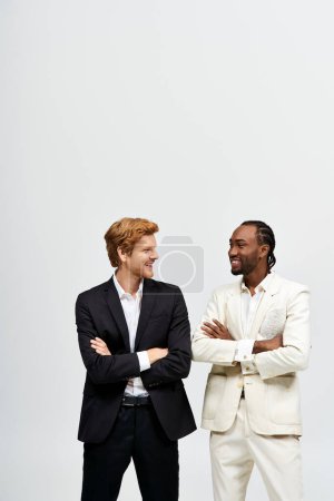 Two handsome men in suits pose elegantly together.