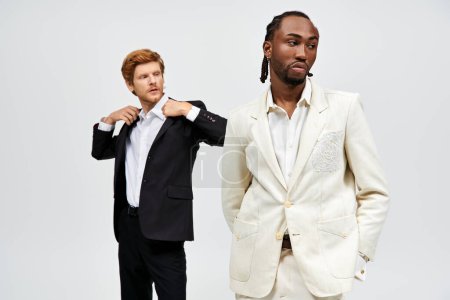 Zwei multikulturelle Männer in eleganten Anzügen posieren selbstbewusst.